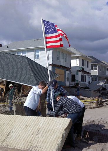 Young men raising the flag after Hurricane Sandy devastation.